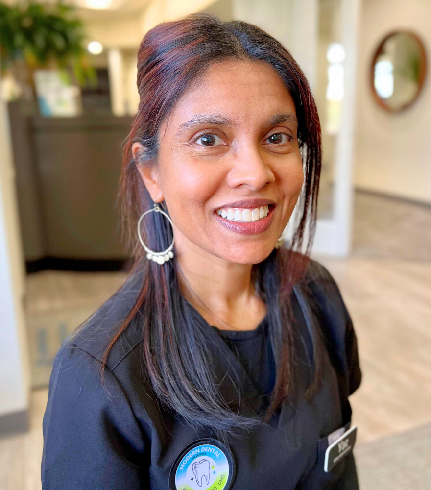 Office administrator smiling to represent the welcoming and organized front desk team at Modern Dental of Durham